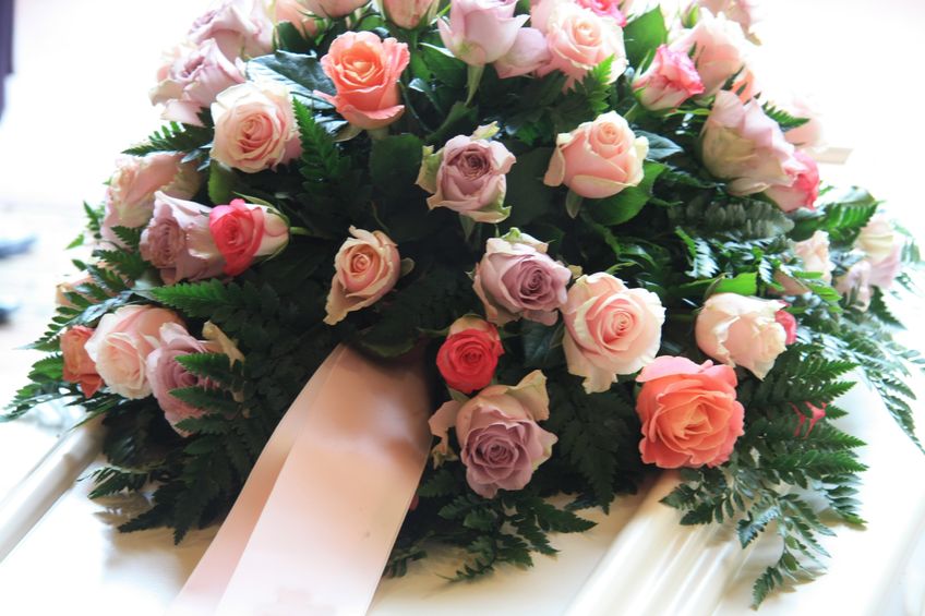 10433838 - pink sympathy flowers with a pink ribbon on a white coffin